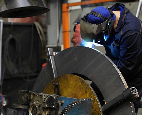 Operatore STAM durante la saldatura di un componente metallico curvo